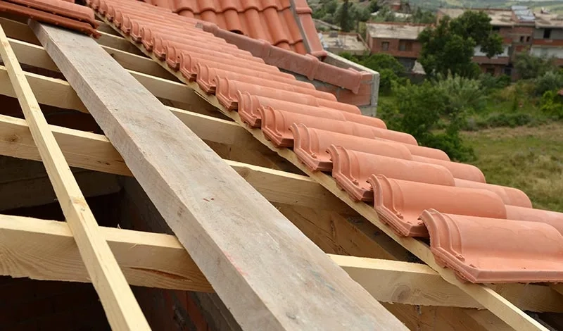 Pose de tuiles sur une charpente en bois par BATI ZINC 31, montrant les liteaux et les premières rangées de tuiles